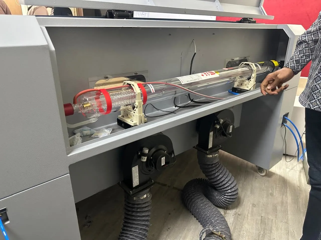 Inside the laser cutter, with a student pointing at the laser tube.