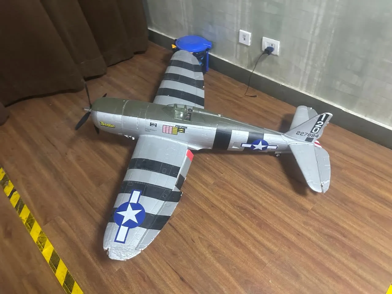 A radio-controlled warbird model on the lab floor.