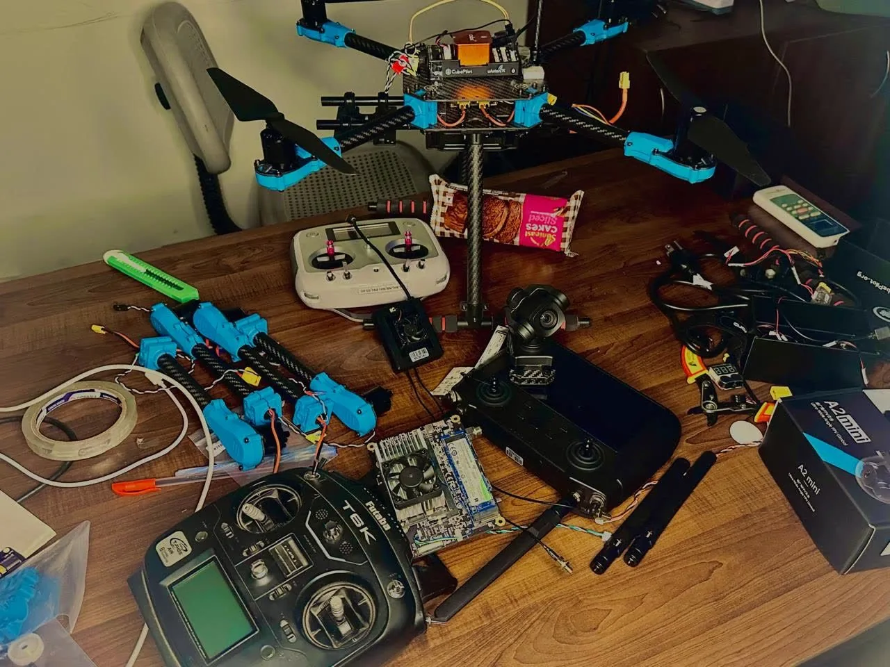 Quadcopter frame, controller and parts laid out on a table.